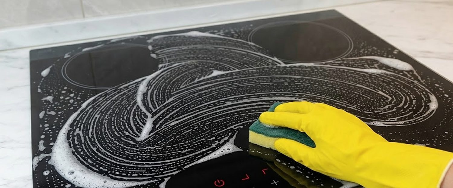 Glass hob being scrubbed by hand during a cleaning visit