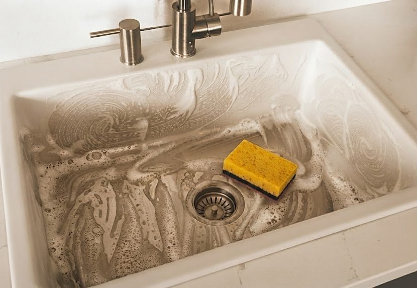 Kitchen sink filled with grey suds, sponge resting by the drain